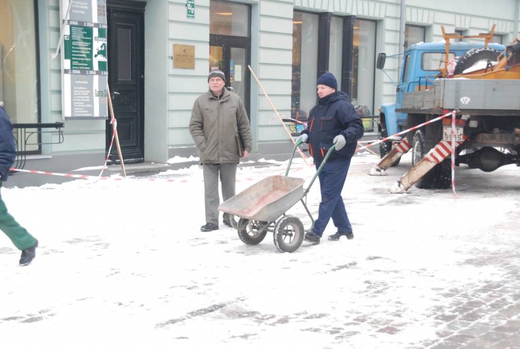 Valsts Nekustamo īpašumu aģentūra no apsaimniekojamo namu jumtiem Tirgoņu ielā novāc sniegu, kas bīstami pārkāries pāri jumta malai.