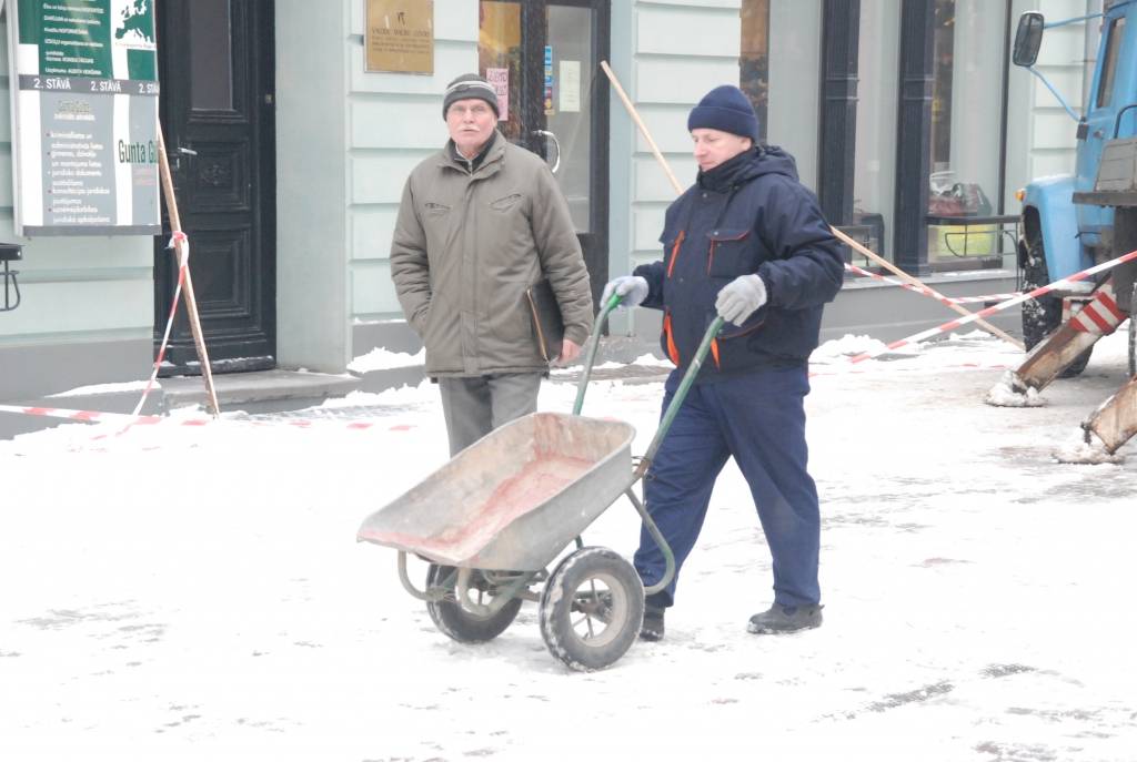 Valsts Nekustamo īpašumu aģentūra no apsaimniekojamo namu jumtiem Tirgoņu ielā novāc sniegu, kas bīstami pārkāries pāri jumta malai.