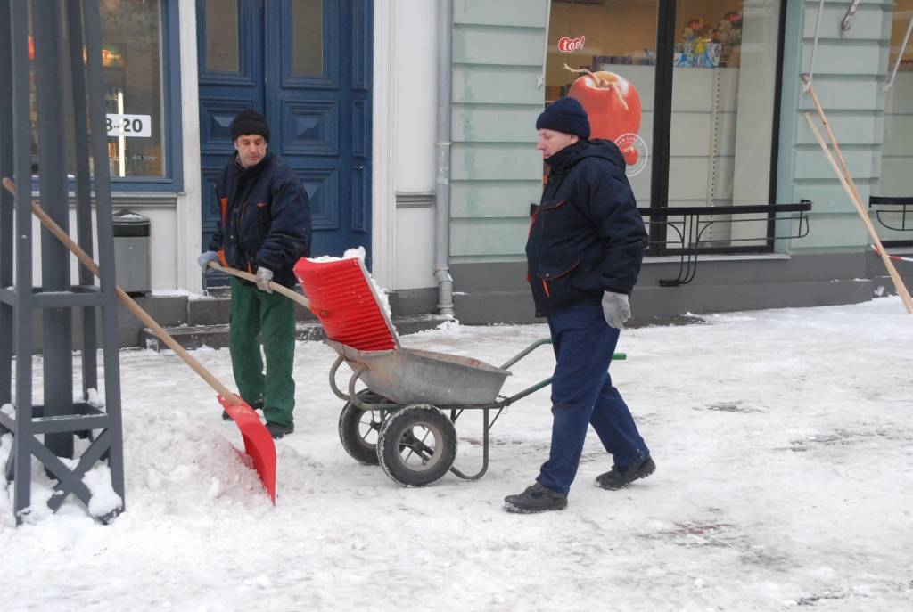 Valsts Nekustamo īpašumu aģentūra no apsaimniekojamo namu jumtiem Tirgoņu ielā novāc sniegu, kas bīstami pārkāries pāri jumta malai.