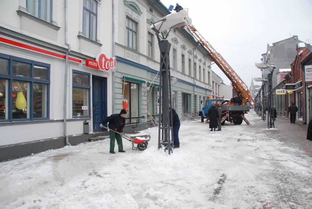 Valsts Nekustamo īpašumu aģentūra no apsaimniekojamo namu jumtiem Tirgoņu ielā novāc sniegu, kas bīstami pārkāries pāri jumta malai.